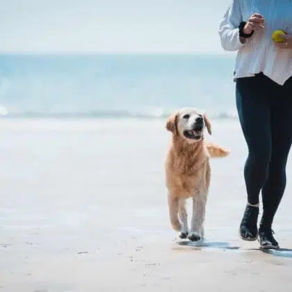 Fit Young woman running with her dog on the beach